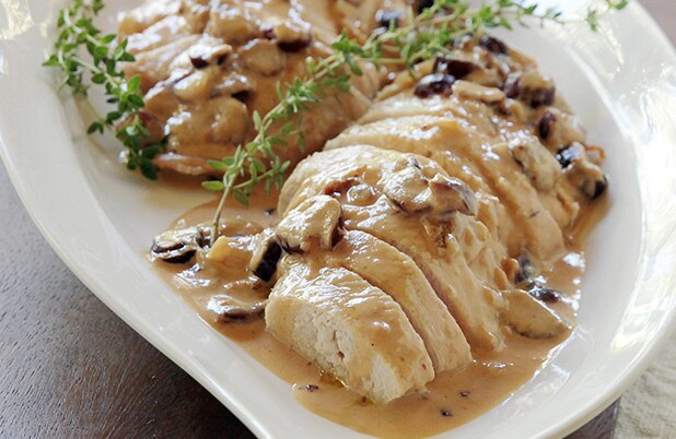 Una fuente de pavo en rodajas con arándanos, salsa chipotle y guarnición de romero.